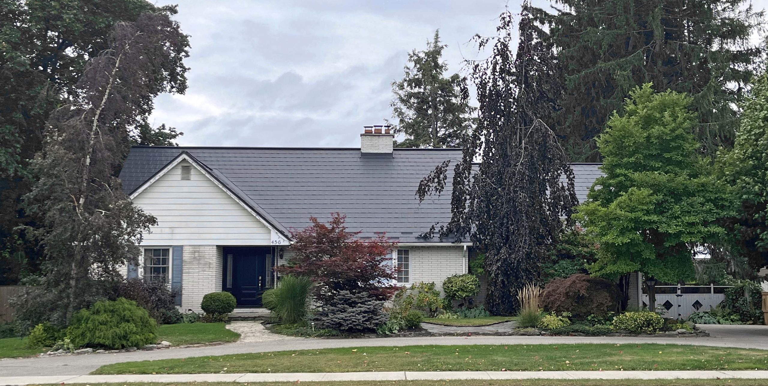 456 Talbot St.W. A two-storey-home, ranch-style, with a semicircular driveway. Partially obscured by lush gardens.