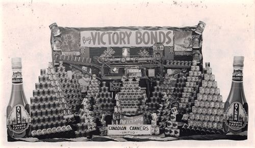 stack of cans with Aylmer branding below a banner which reads "Buy Victory Bonds"