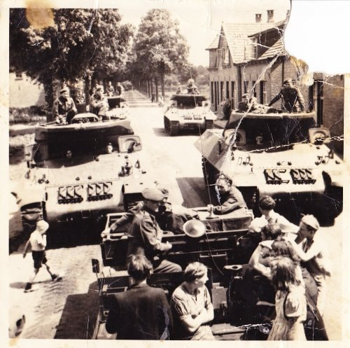 Four armoured tanks in the road of a European town.