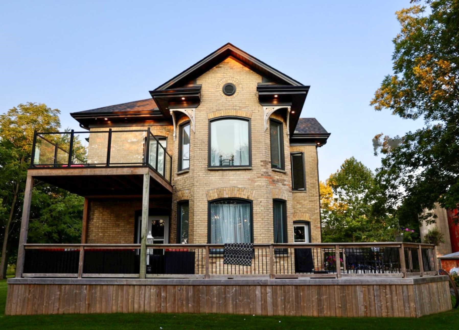 11480 Springfield Road. A two-storey yellow brick home with beautiful modern upgrades. Features a balcony, a wrap-around porch, and bay windows.