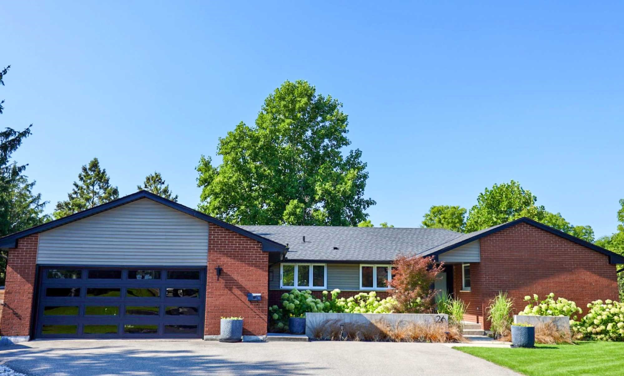 26 Lawrence Crescent. A mid-century, red, brick, single-storey building with a two-car garage.