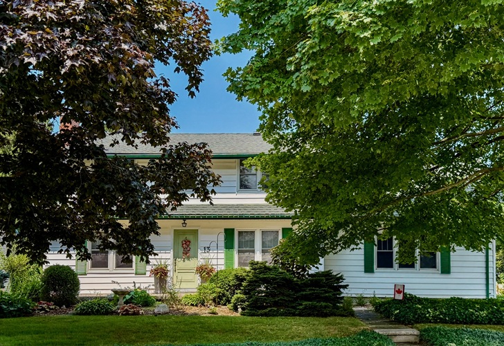 A two-storey house with white siding and green trim